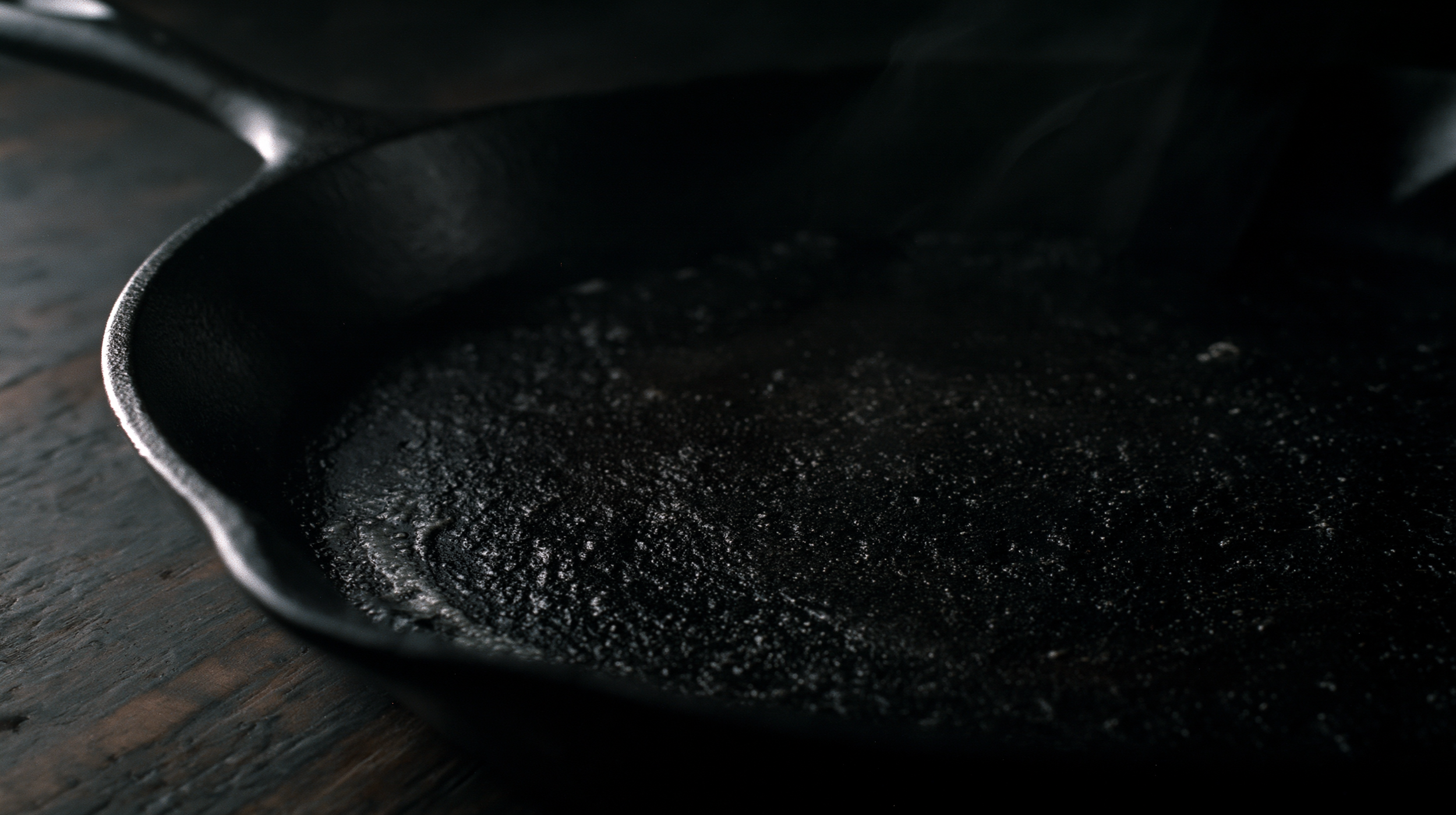 Seasoned cast iron skillet with dark patina on aged wood